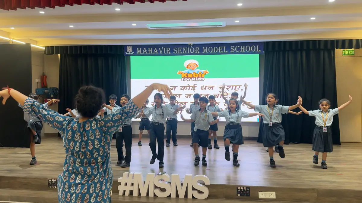 Shivani guiding Class 2 children through the koyal song on the school stage during a rehearsal