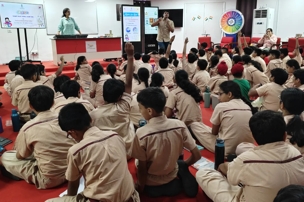 A hundred Class 6 students from Vasant Valley School, hands raised mid-doha at the NBT Vasant Kunj auditorium, May 2026